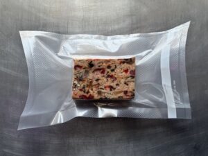A slice of fruitcake encased in plastic.